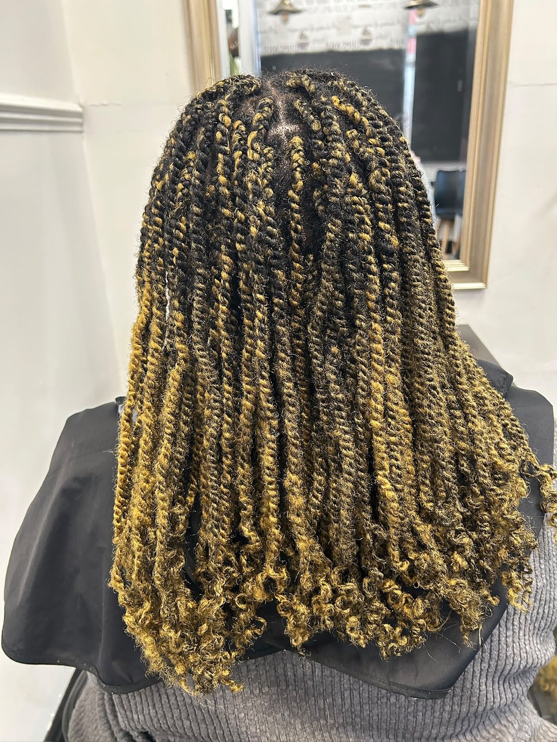 Black and honey blonde twists with curled ends, seen from behind