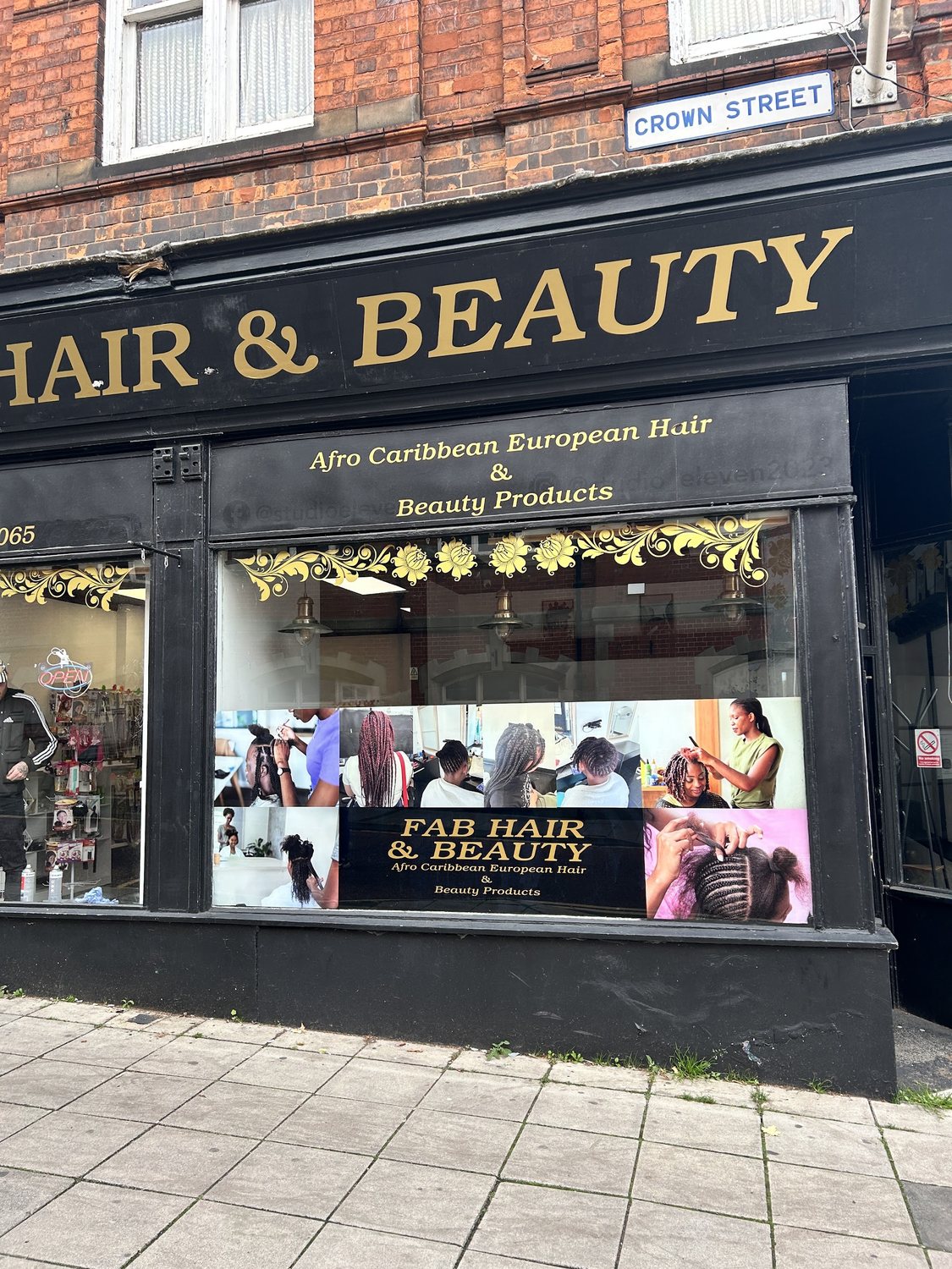 The shop window on Crown Street: gold lettering on black, reading Afro Caribbean European Hair and Beauty Products
