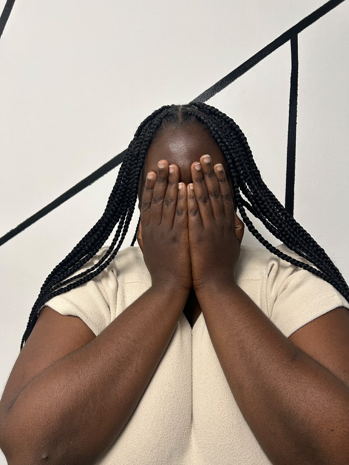 Long black box braids, the client hiding her face behind her hands