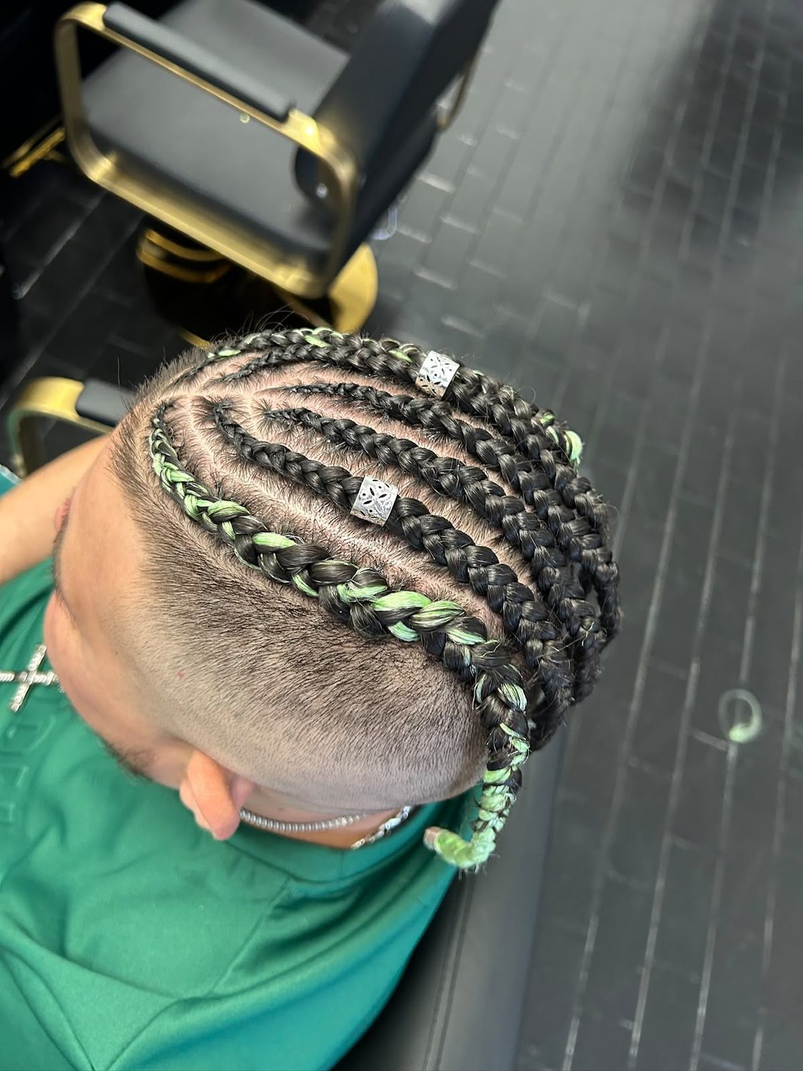 Men’s cornrows with green braiding hair and silver cuffs on a faded cut
