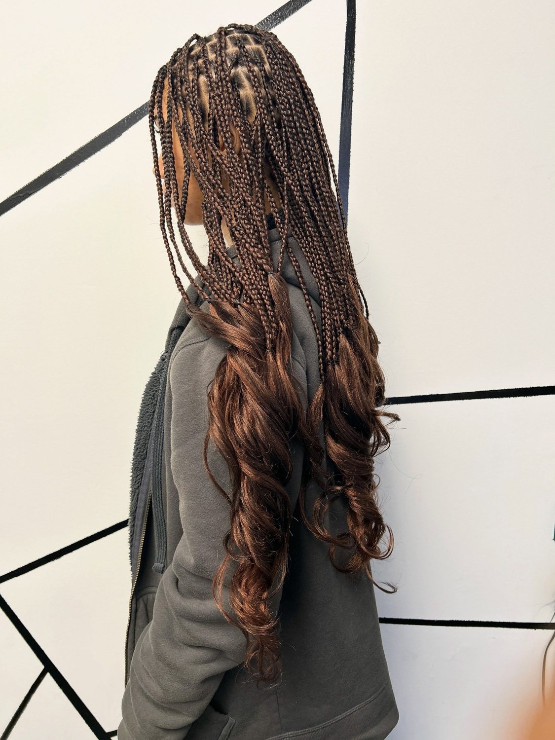 Long brown braids finished with loose curls, seen from the side