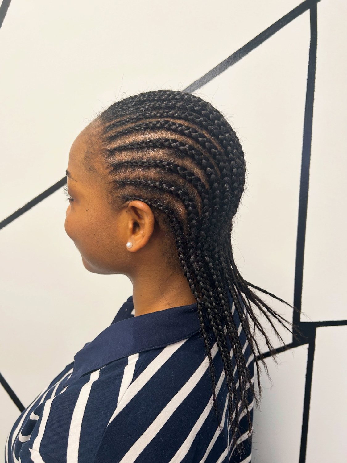 Neat straight-back cornrows on a smiling client, side view